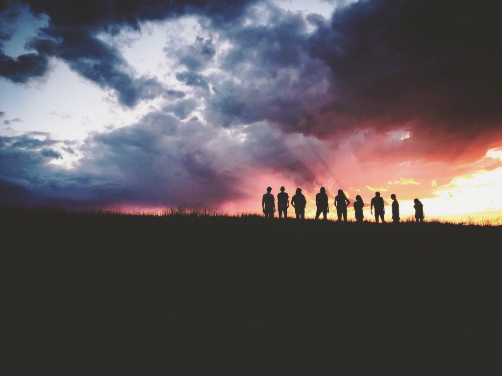 silhouette of nine persons standing on the hill